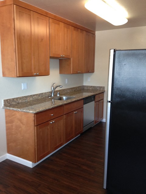 a kitchen with wooden cabinets and a black refrigerator